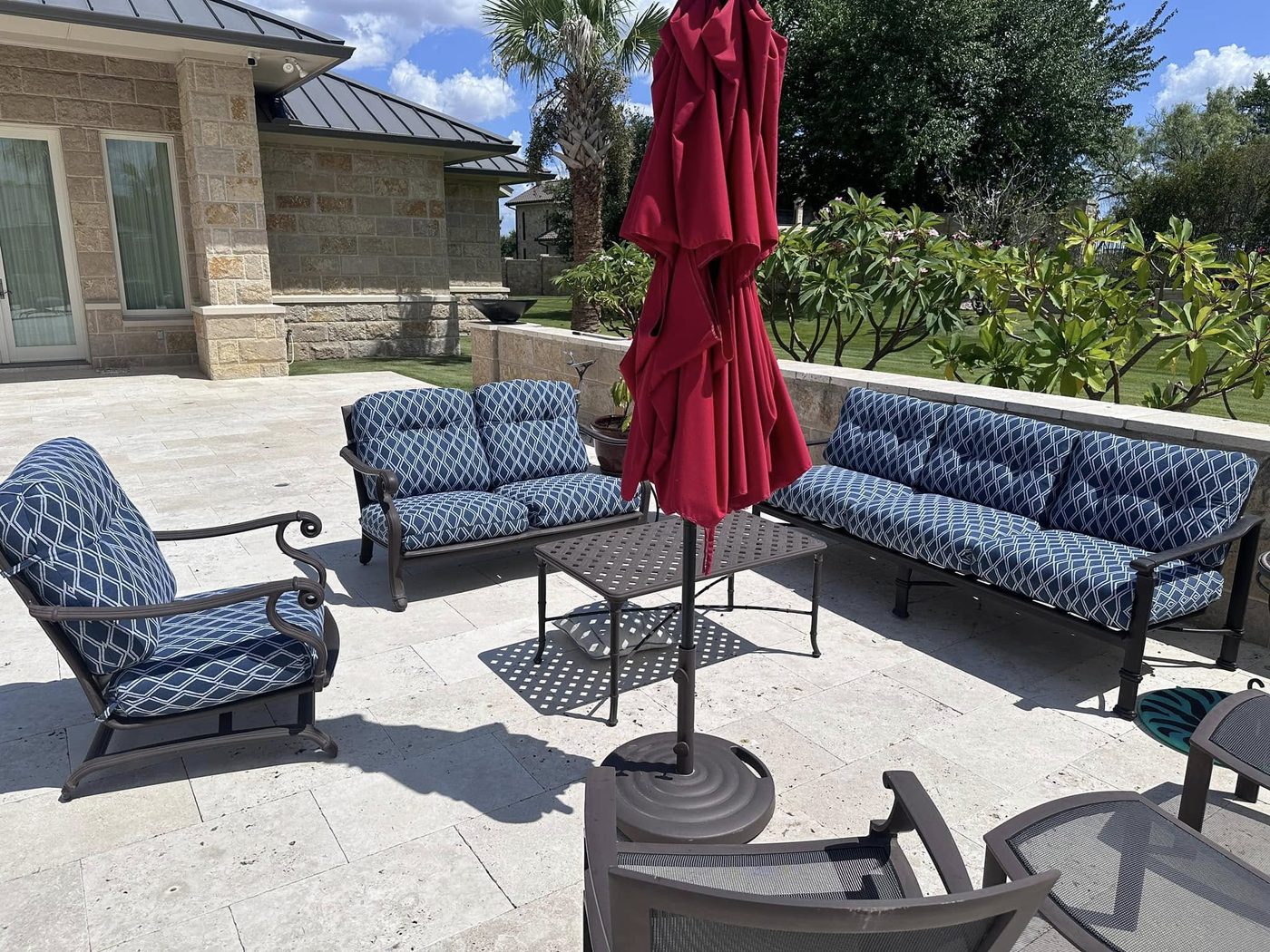 Patio set with blue cushions and a red umbrella