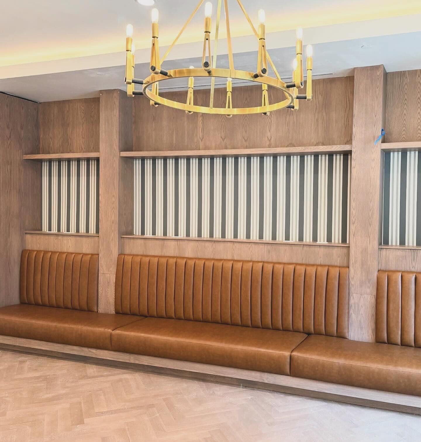 Restaurant interior with leather banquettes and brass chandeliers